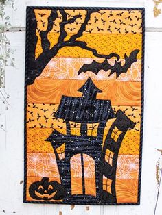 a quilt hanging on the side of a building with pumpkins and bats around it