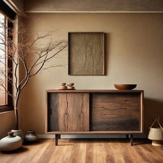 a wooden cabinet sitting in front of a window next to a potted plant and vase