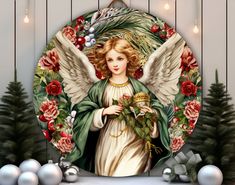 an angel surrounded by christmas decorations and ornaments in front of a white background with red roses