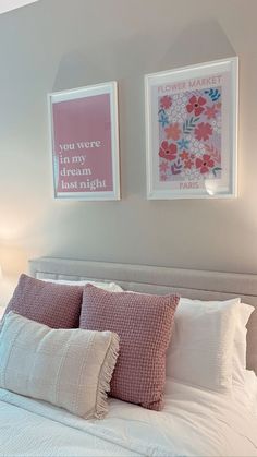 two framed pictures hang on the wall above a bed with white linens and pillows