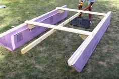 a man is working on some kind of wooden structure in the grass with his tools