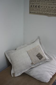 two white pillows sitting on top of a wooden table next to a wall with an old book