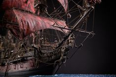 an old pirate ship with red sails and ropes on the mast is shown against a black background