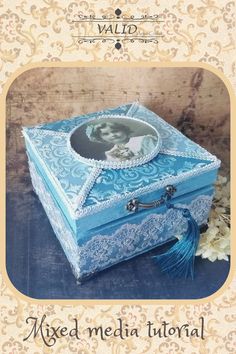 an ornate blue box with a photo on it and a tassell around the edge