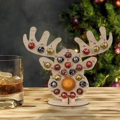 a wooden reindeer ornament sitting on top of a table next to a glass of alcohol