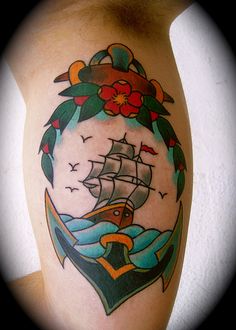 a tattoo with an anchor and ship on it's side, surrounded by flowers