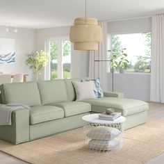 a living room filled with furniture next to a window covered in white curtains and pillows