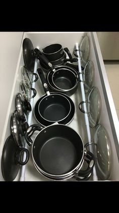 pots and pans are lined up on the counter in this kitchen drawer with black lids