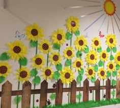 a wall with sunflowers painted on it and a wooden fence in the foreground