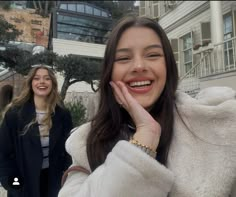 two women walking down the street and one is holding her hand up to her face