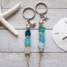 two keychains with beads and charms on them next to a starfish shell