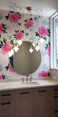 a bathroom with floral wallpaper and large round mirror