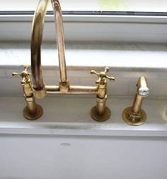 three brass faucets are on the side of a window sill