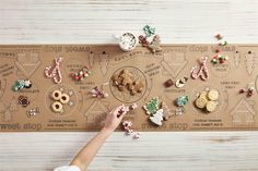 a person is placing buttons on a board with christmas decorations and cookies in the shape of houses