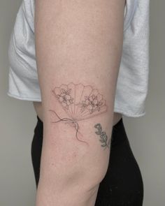 a woman with a tattoo on her arm holding a flower in one hand and a butterfly in the other