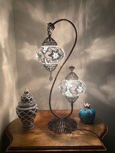 an ornate lamp on top of a table next to two vases and a candle holder