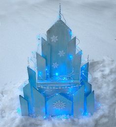 an ice sculpture with blue lights and snowflakes on it's sides in the snow