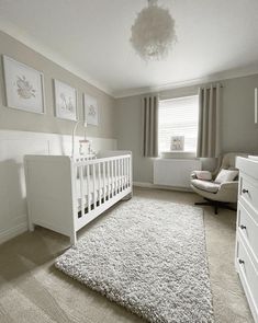 a baby's room with a white crib, dresser and chair in it