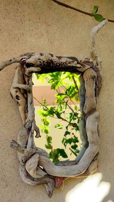 a mirror made out of driftwood on the side of a building with a tree branch sticking out of it