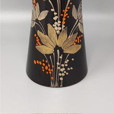 a black vase with orange and white flowers on it