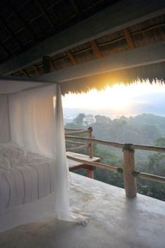 a canopy bed sitting on top of a wooden floor next to a lush green hillside