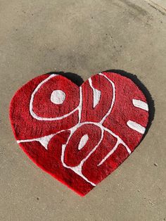 a heart shaped rug with the word love painted on it