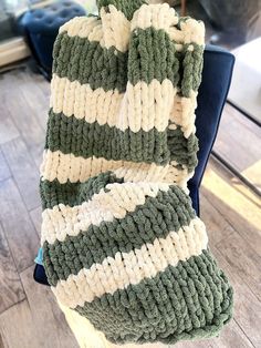 a green and white blanket sitting on top of a chair