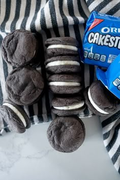 chocolate cookies and oreo cookies are arranged on a striped towel next to a bag of oreos