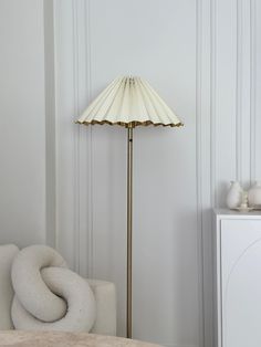 a lamp that is on top of a table next to a white chair and cabinet