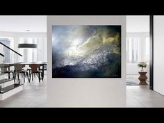 an abstract painting hangs in the middle of a room with white walls and flooring