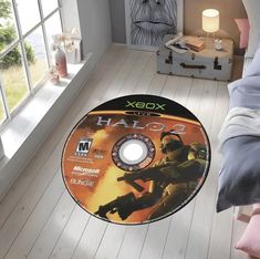 a video game disc sitting on the floor in front of a bed with a window