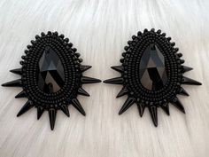 two black earrings with spikes are on a white surface