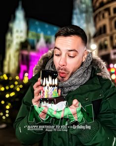 a man holding a birthday cake with candles on it in front of a cityscape