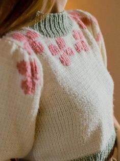 a close up of a woman wearing a sweater and holding a cell phone in her hand