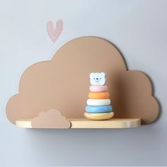 a toy bear sitting on top of a shelf next to a cloud shaped wall decoration