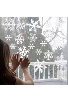 a girl is looking out the window at snowflakes