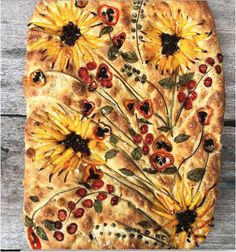 a pizza with sunflowers and cherries on it sitting on top of a wooden table