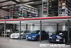 three cars are parked in a garage with stairs