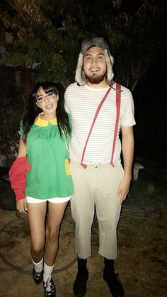 a man and woman standing next to each other in front of a tree at night