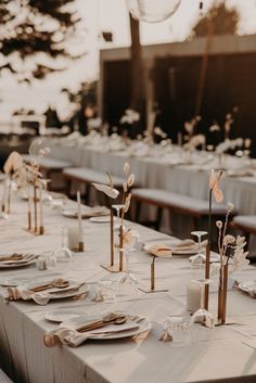 a long table is set with white linens and gold place settings for an event