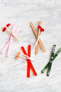 four popsicle sticks are lined up on a white marble surface with green and red toothpicks sticking out of them