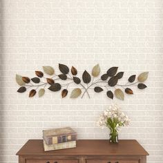 a wooden dresser with two drawers and a metal wall decoration on it's side