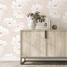 a white vase with flowers on top of a wooden cabinet next to a wallpaper