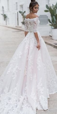 a woman in a white wedding dress standing on the sidewalk with her hand on her hip