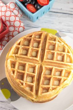 a waffle on a plate with berries in the background