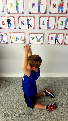 a young boy sitting on the floor with his hands up in front of letters that spell out