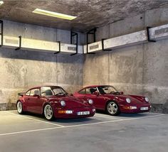 two red porsches are parked in a parking garage with concrete walls and flooring