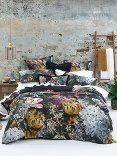 a bed with flowers on it in front of a brick wall and potted plant