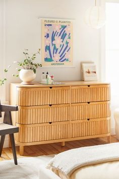 a bedroom with a dresser, chair and painting on the wall