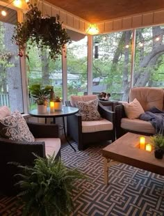 a screened porch with wicker furniture and potted plants on the table, surrounded by candles